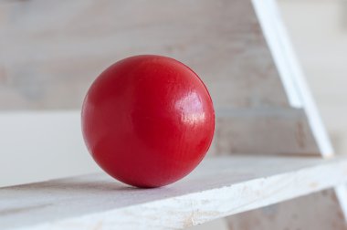 Red plastic ball on white shelf, light background clipart