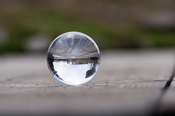 Glass transparent ball on dark green background and wooden surface. Soft focus. With empty space for text — Stock Photo, Image