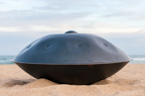 Klid hudební pozadí. Ruce bicí. Zablokování nebo handpan s mořem v pozadí. Pověste je tradiční etnické bicí hudební nástroj — Stock fotografie