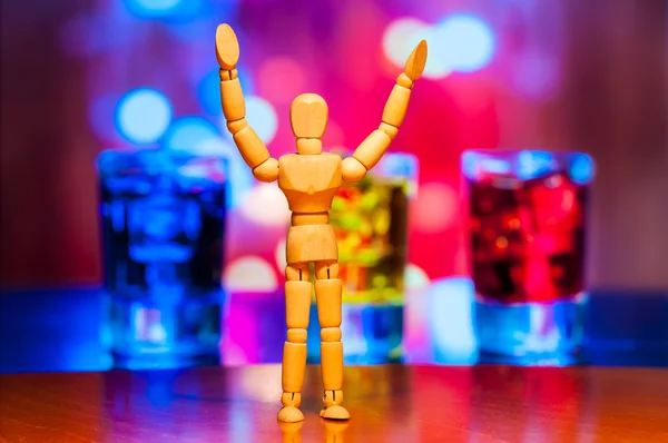 Happy wooden dummy, mannequin or man figurine, silhouette stand against the backdrop of alcohol drinks. Friday background — Zdjęcie stockowe