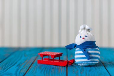 Kırmızı kızak ve açık ahşap renkli küçük el yapımı kardan adam. Metin boş alanı ile Noel kartı