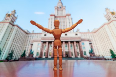 Wooden man against backdrop of the main building Of Lomonosov Moscow State University on Sparrow Hills in Moscow, Russia