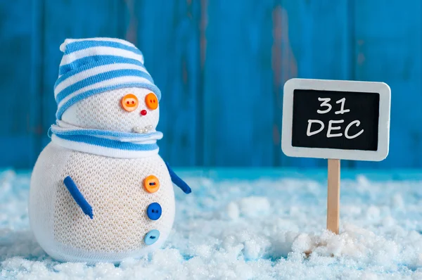 Save the Date for New Year with this handmade snowman in cap near sidepost December 31. Winter holiday background — стокове фото