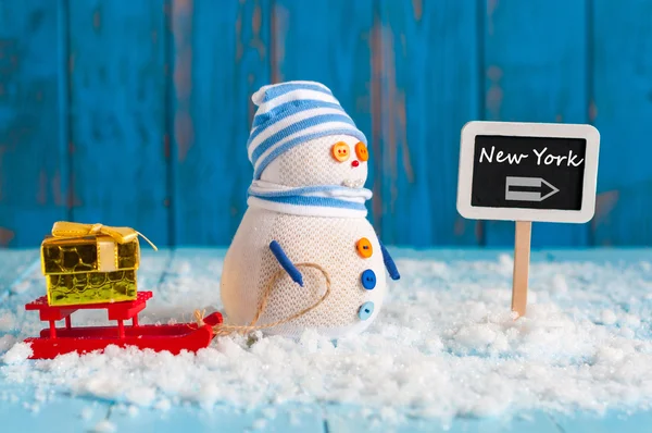Signpost of the famous New York,  USA and Snowman with red sled stand near direction sign. Christmas And new year postcard — Stockfoto