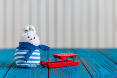 Kırmızı kızak ve açık ahşap renkli küçük el yapımı kardan adam. Metin boş alanı ile Noel kartı