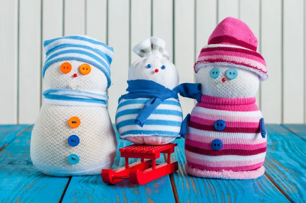 Handmade snowman family wearing scarf and knitted cap on wooden background, merry Christmas, New year postcard — Stockfoto