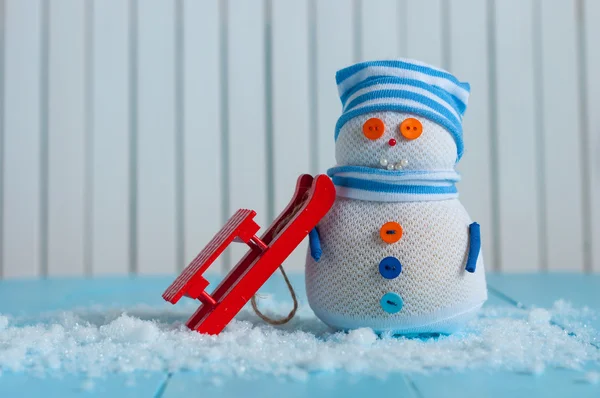 Handmade snowman stay with red sled on light wooden background. Happy Christmas card, empty space for Text — Stockfoto