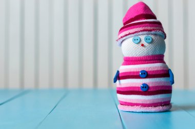 Snowman wearing striped sweater on blue wooden background, merry Christmas. With empty space for content text
