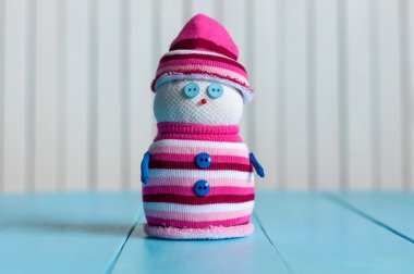 Snowman wearing striped sweater on blue wooden background, merry Christmas. With empty space for content text