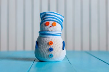 Snowman wearing striped sweater on blue wooden background, merry Christmas. With empty space for content text