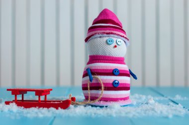 Kırmızı kızak ve ahşap arka plan olarak el yapımı kardan adam. Metin boş alanı ile Noel kartı