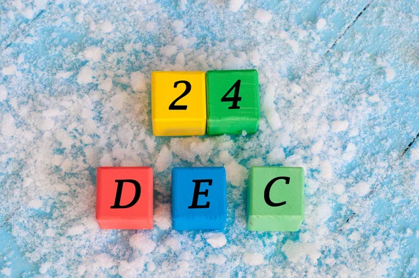 24 dicembre segno su cubi di legno a colori con neve e sfondo azzurro. Concetto di Natale invernale — Foto Stock