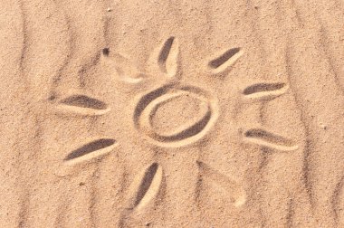 simple sun drawing in the sand on The beach. Summer travel concept