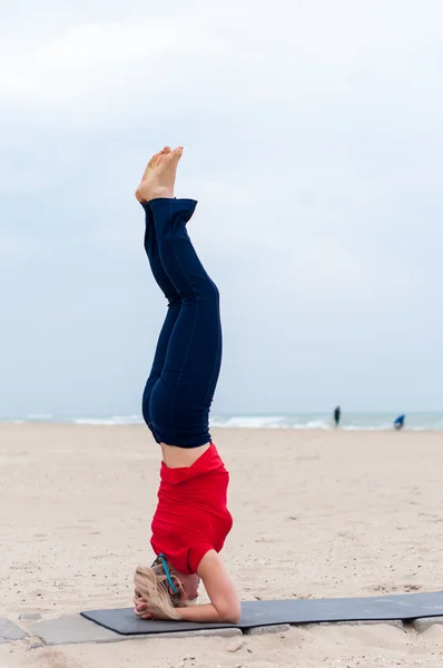 Sporty woman doing Supported Headstand, yoga asana Sirsasana, Shirshasana, Sirshasana, Headstand on sea  background — Stock fotografie