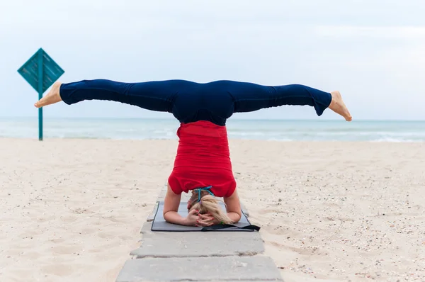 Woman doing yoga asana upavishtha konasana shirshasana, Bound Angle Pose in Head Stand on sea background — Stock Photo, Image