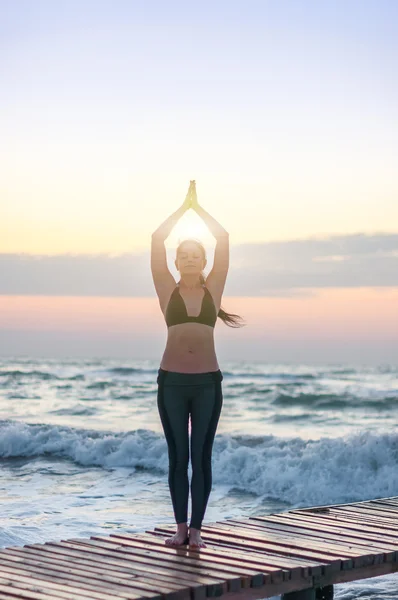 Osvícený mladá žena relaxaci na pláži, meditace v asana hasta uttanasana, ruce v gestu Namaste na západ nebo východ slunce, zblízka — Stock fotografie