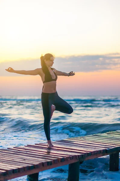 Mladá žena je cvičení jógy s první paprsek slunce na pozadí oceánu. Zdravé, sportovní koncept životní styl — Stock fotografie