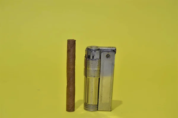 An object of Lighter isolated. Orange lighter and small size cuban cigar with isolated background.