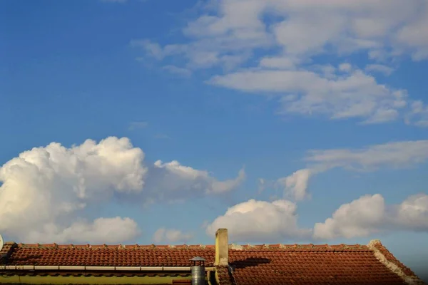Red and cement tile roofing and smoke hole with blue sky and white clouds background. Bursa Turkey during bright day.