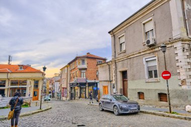 06.01.2021. Plovdiv. Bulgaristan. Plovdiv 'de halka açık ve sıradan bir gün. Gün batımında ve bulutlu havada cadde ve küçük dükkanlar kaldırım taşı yollar ve patika yollar.