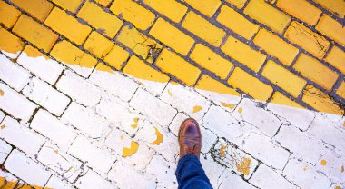 Sofya 'da kahverengi çizme giyen erkek yiyeceği, canlı sarı ve beyaz kaldırım taşı ve yaya yolunda kalıyor.