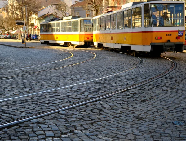 Çarşıya yakın eski sarı tramvay, kaldırım taşının üzerinde kadın çarşısı, etrafta yürüyen insanlar ve caddeye park eden arabalar diye seslendi..