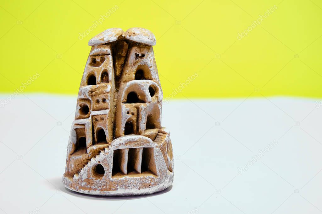 Miniature fairy chimney trinket made of gypsum block. Isolated yellow background and white ground. 