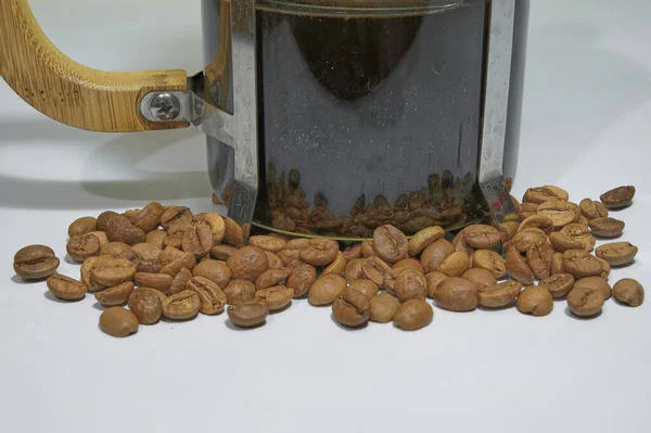 プレスと木製の詳細のガラス側の中に調理されたカフェ 白い地面にフランスのプレスコーヒーメーカー フランス紙のアラビアコーヒー豆と一緒に — ストック写真