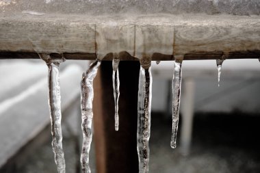 Kapalı ve küçük bir buz saçağı parçası ve küçük bir su damlası ahşap masa üzerinde var Kış ve soğuk gün boyunca dışarıda kalın.