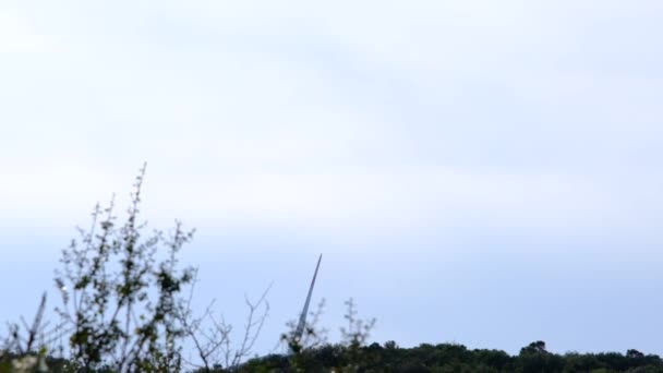 丘や木の一部からの風力タービンプロペラのスローモーションビデオ — ストック動画