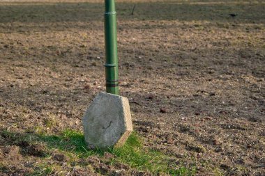 Altıgen şeklinde ve yeşil sokak lambalarıyla desteklenen bir taş. Toprakta ve çamurda duran taş. 