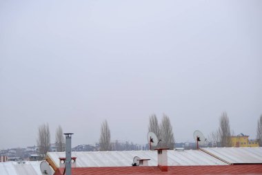 Bursa, Türkiye 'de hava bulutluyken metal çatı, bacalar ve uydu antenleri.
