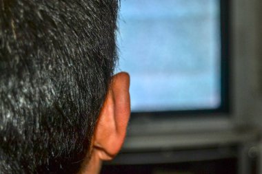 Yalnız bir adam televizyon izliyor. Adamın ve kafasının arkasında fotoğraf var. Eski tarz ve tüp televizyonlarda da kumlu ekran var..