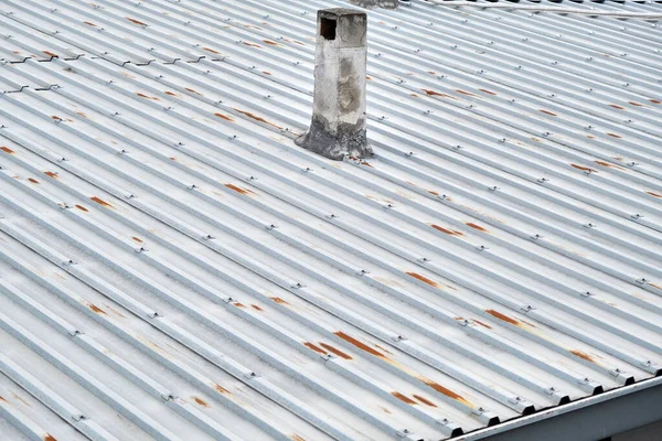 Evin çatısı metal panellerden yapılmış. Çatıda aşınma ve bulutlu havada eski usul baca yığını var.