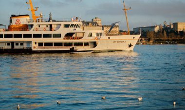 26.02.2021. İstanbul. Hindi. Sabahın erken saatlerinde Bosporus deniz iç taşımacılığı feribotu ve feribotta güneş yansıması. Feribot ve etrafında bir sürü martı.. 