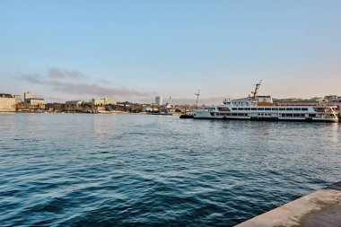 26.02.2021. İstanbul. Hindi. Sabahın erken saatlerinde Bosporus deniz iç taşımacılığı feribotu ve feribotta güneş yansıması. Feribot ve etrafında bir sürü martı.. 