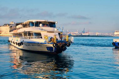 26.02.2021. İstanbul. Hindi. Sabahın erken saatlerinde Bosporus deniz iç taşımacılığı feribotu ve feribotta güneş yansıması. Feribot ve etrafında bir sürü martı.. 