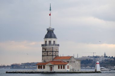 İstanbul, Türkiye 'deki Bakire Kulesi (kz kulesi), boğaz denizinde güneş ışığının yansımasıyla bulutlu havalarda görülüyor. Denizde uçan martı grupları. Türkiye 01.03.2021