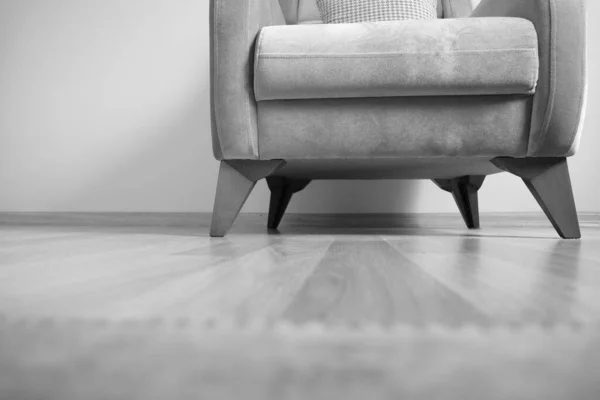 Black and white photo of single seat and minimalism. Old vintage and retro style single seating chair standing on wooden floor and its legs made of wooden material.