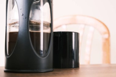 Fransız kahve makinası. Yarısı Arap ve siyah kahve makinesiyle dolu. Yanında da siyah kahve demliği ve ahşap koltuğun üst tarafı. Her şey ahşap masada duruyor..