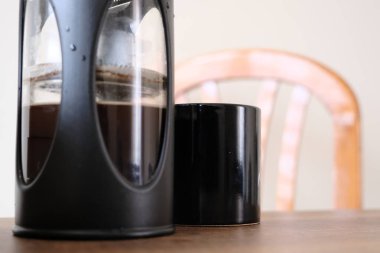 Fransız kahve makinası. Yarısı Arap ve siyah kahve makinesiyle dolu. Yanında da siyah kahve demliği ve ahşap koltuğun üst tarafı. Her şey ahşap masada duruyor..