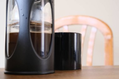 Fransız kahve makinası. Yarısı Arap ve siyah kahve makinesiyle dolu. Yanında da siyah kahve demliği ve ahşap koltuğun üst tarafı. Her şey ahşap masada duruyor..