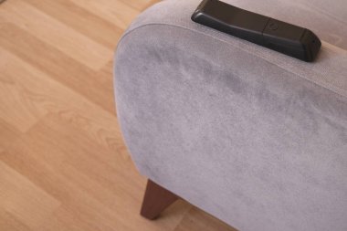 En eski, eski, modası geçmiş koltuk ve minimalizm sembolü. Eski model ve retro tek koltuklu televizyon kumandanı, şablonlu yastık ve ahşap arka planda duruyor..