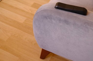 En eski, eski, modası geçmiş koltuk ve minimalizm sembolü. Eski model ve retro tek koltuklu televizyon kumandanı, şablonlu yastık ve ahşap arka planda duruyor..