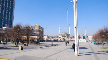 Hindi. İstanbul 04.03.2021 İstanbul, güneşli bir günde Taksim Meydanı 'nın en tanınmış meydanlarından biri. Taksim camii, insanlar turist ve polis geziyor. Meydan her zamanki gibi kalabalık değil..