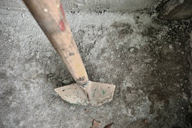 Yakın zamanda yapılmış betonla sıvanmış duvarın önündeki kürek. Küreğin metal tarafında yeşil renkler var. İnşaat bittikten sonra. fotoğraf yüksek açılı çekildi