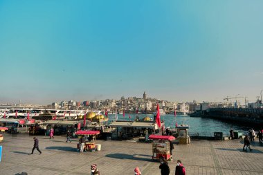 04.03.2021 İstanbul Türkiye. Eminonu bölgesindeki Bosphorus istanbul 'da ünlü bir sokak yemeği satıcısı. Suya yakın ızgara balık tekneleri ve Türk bayrakları ve galata kulesi ile Bosporus kıyıları..
