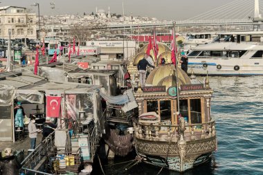 04.03.2021 İstanbul Türkiye. Eminonu bölgesindeki Bosphorus istanbul 'da ünlü bir sokak yemeği satıcısı. Suya yakın ızgara balık tekneleri ve manu Türk bayrağı ve antik tekneler ile Boğaz kıyısı.
