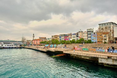 Türkiye istanbul 03.03.2021. Karaköy kıyısı ve oturma alanı üzerinde renkli bir tablo ve İstanbul 'da altın boynuz, boğaz ve genç çiftlerin konuştuğu balıkçı oltasıyla bekleyen bir adam.