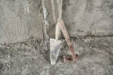 Yakın zamanda yapılmış betonla sıvanmış duvarın önünde mala ve adze. Ahşap malzemeden yapılmış adzanın sapında kırmızı renkler var. inşaat çalışmalarından sonra.